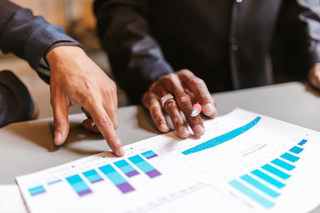 hands pointing to graphs on a piece of paper 